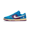 Zijaanzicht van de blauwe Nike Dunk Low x Undefeated 5 on It met paarse snakeskin Swoosh.
