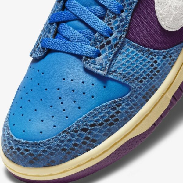Close-up van de geweven zijpanelen en suede overlays op de Undefeated Dunk Low.